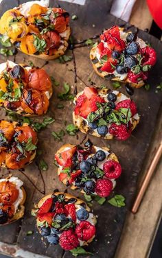 small appetizers are arranged on a cutting board with strawberries and blueberries