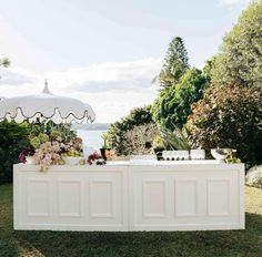 an outdoor bar with flowers and candles on it in front of the water, surrounded by greenery