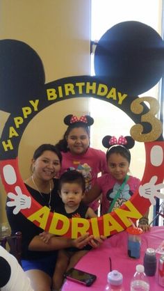 a group of people that are standing in front of a table with a mickey mouse sign