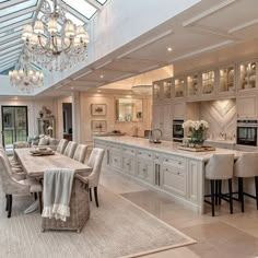 a large kitchen with an island and dining table in the center, surrounded by beige chairs