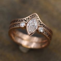 a close up of a ring with a diamond on the top and an intricate band around it