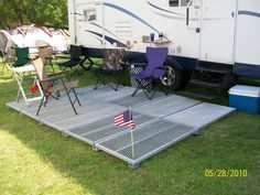 an american flag is placed on the ground in front of a camper and chairs