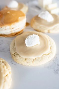 some cookies with icing and marshmallows on them sitting on a table