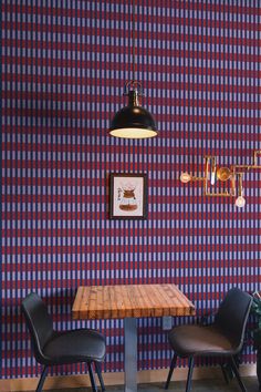 two black chairs sitting at a wooden table in front of a wall with checkered pattern