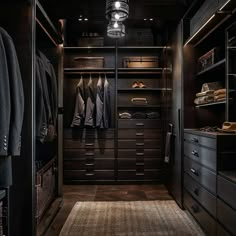 a walk in closet with dark wood cabinets and drawers