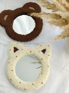 two teddy bear shaped mirrors sitting on top of a white table next to dried grass