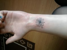 a person's arm with a small flower tattoo on the left side of their hand