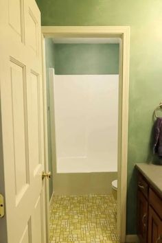 a bathroom with green walls and yellow tile flooring on the shower wall, along with an open door that leads to a walk - in closet