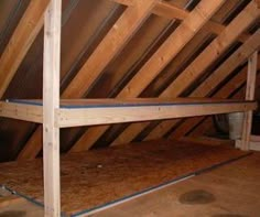 an attic with wooden beams and exposed floor joisting on the bottom half of it