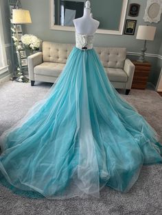 a dress on display in a room with a couch and mirror behind it, all dressed up