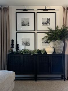 a living room with pictures on the wall and plants in vases sitting on top of it