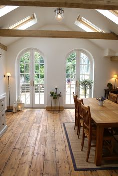 a large open kitchen and dining room area with wooden floors, white walls and vaulted ceiling