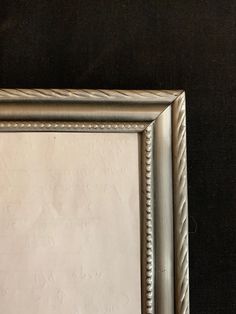 an old silver framed mirror on a black background with white stitching around the edges