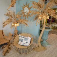 a wicker chair sitting under a palm tree next to a table with two lamps on it