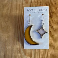 a pair of earrings sitting on top of a wooden table in front of a card