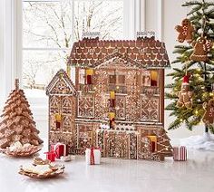 an elaborate gingerbread house next to a christmas tree