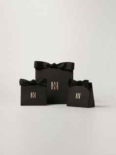 three black gift bags with gold monogrammed letters and bows on them, one has a bow at the top