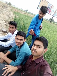 three men are sitting in the grass and one is holding something