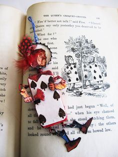 an open book with a red and black alice in wonderland decoration on it's cover