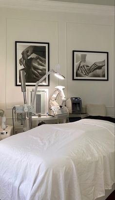 a white bed sitting in a bedroom next to two pictures on the wall above it