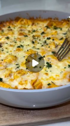 a fork in a casserole dish with cheese and spinach on it, ready to be eaten