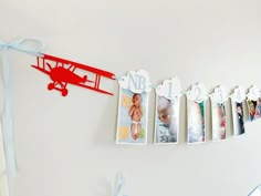 a red airplane is hanging on the wall next to some baby's first year pictures