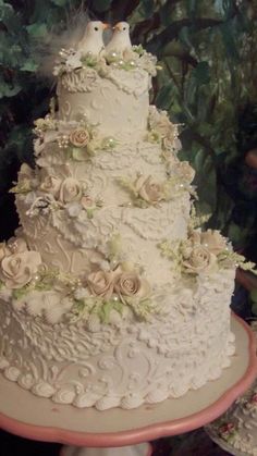 a three tiered wedding cake with flowers and birds on top