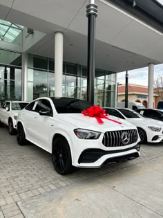 two white mercedes cars with a red bow tied to the front and side of them