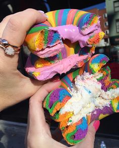 a person holding some colorful doughnuts with icing and sprinkles