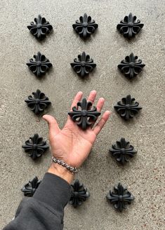 a person's hand is shown in front of several black crosses on the ground