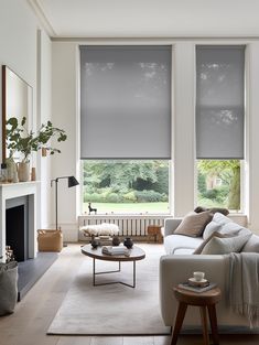 a living room filled with furniture and windows covered in roman blind shades on the windows