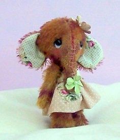 a small stuffed elephant wearing a pink dress and flowered headband with her eyes closed