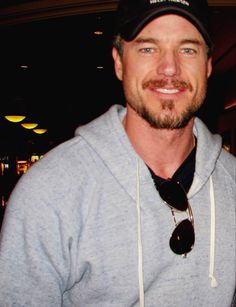 a man wearing a hat and sweatshirt posing for the camera