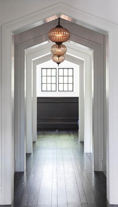 an open hallway with white walls and wooden floors, light fixture hanging from the ceiling