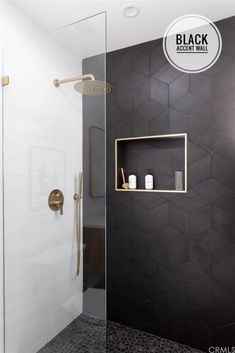 a black and white bathroom with hexagonal tiles on the wall, shower head, and shelves