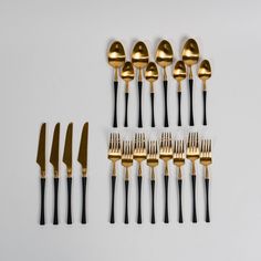 gold and black forks and spoons on a white surface