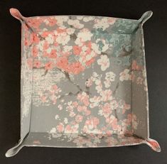 a square tray with pink and blue flowers on the bottom, sitting on a black surface