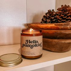 a candle sitting on top of a table next to a potted pine cone and wooden bowl