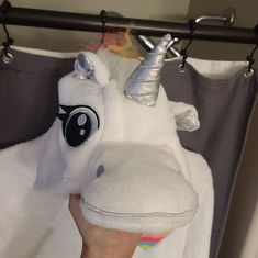 a person is holding up a stuffed unicorn toy in front of a shower curtain with an eye patch on it