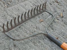 a garden rake laying on the ground with a wooden handle attached to it's blade