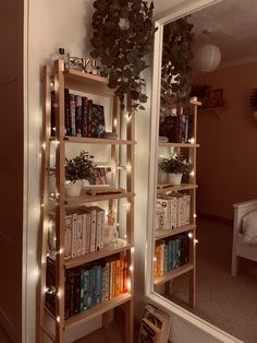 a bookshelf filled with lots of books next to a mirror