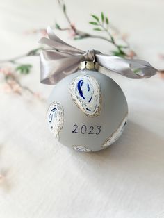 a silver ornament with an angel on it and a ribbon around the top