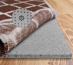 a brown and white blanket laying on top of a wooden floor next to a rug