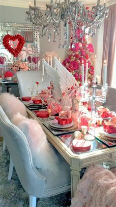 a dining room table set for valentine's day with pink and red decorations on it