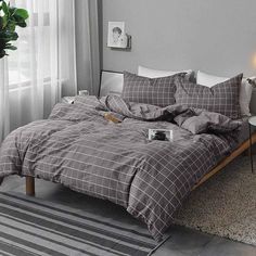 a bed with grey and white plaid comforter in a bedroom next to a window