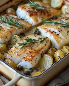 fish and vegetables in a casserole dish with rosemary garnish on top