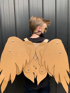 a young boy wearing an angel costume made out of cardboard with wings on his chest