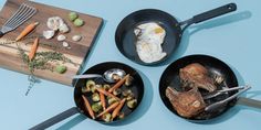 three pans filled with food on top of a wooden cutting board next to utensils