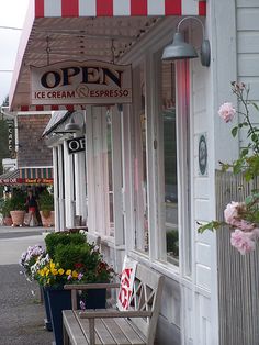 an open ice cream and espresso shop with flowers in the window boxes outside