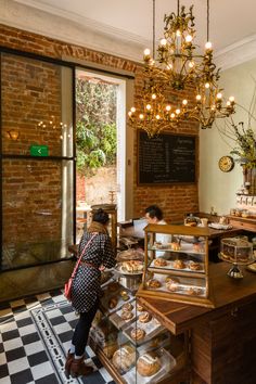 a woman standing in front of a counter filled with pastries